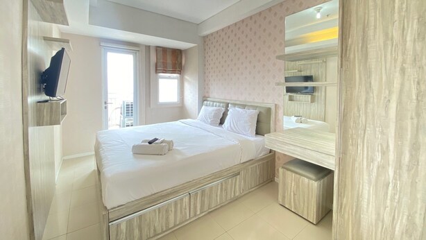 A modern hotel room with a large bed, a built-in wardrobe, and a television. - Nice And Cozy 2Br Apartment At Parahyangan Residence (Bandung)