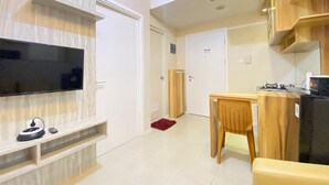 A modern living room with a flat-screen TV, wooden furniture, and a dining area. - Nice And Cozy 2Br Apartment At Parahyangan Residence (Bandung)