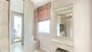A bathroom with a large mirror, a window with curtains, and a tiled floor. - Nice And Cozy 2Br Apartment At Parahyangan Residence (Bandung)