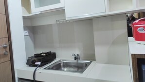 A kitchen with white cabinets, a stainless steel sink, and a red appliance on the countertop. - Convenient Studio At Vida View Makassar (Makassar)