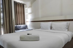 Une chambre d’hôtel avec un lit bien fait, un oreiller sur le lit et une fenêtre avec des rideaux.