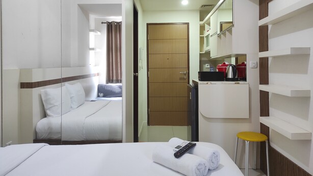 A hotel room with a bed, a bathroom, and a small kitchenette. - Convenient Studio At Vida View Makassar (Makassar)