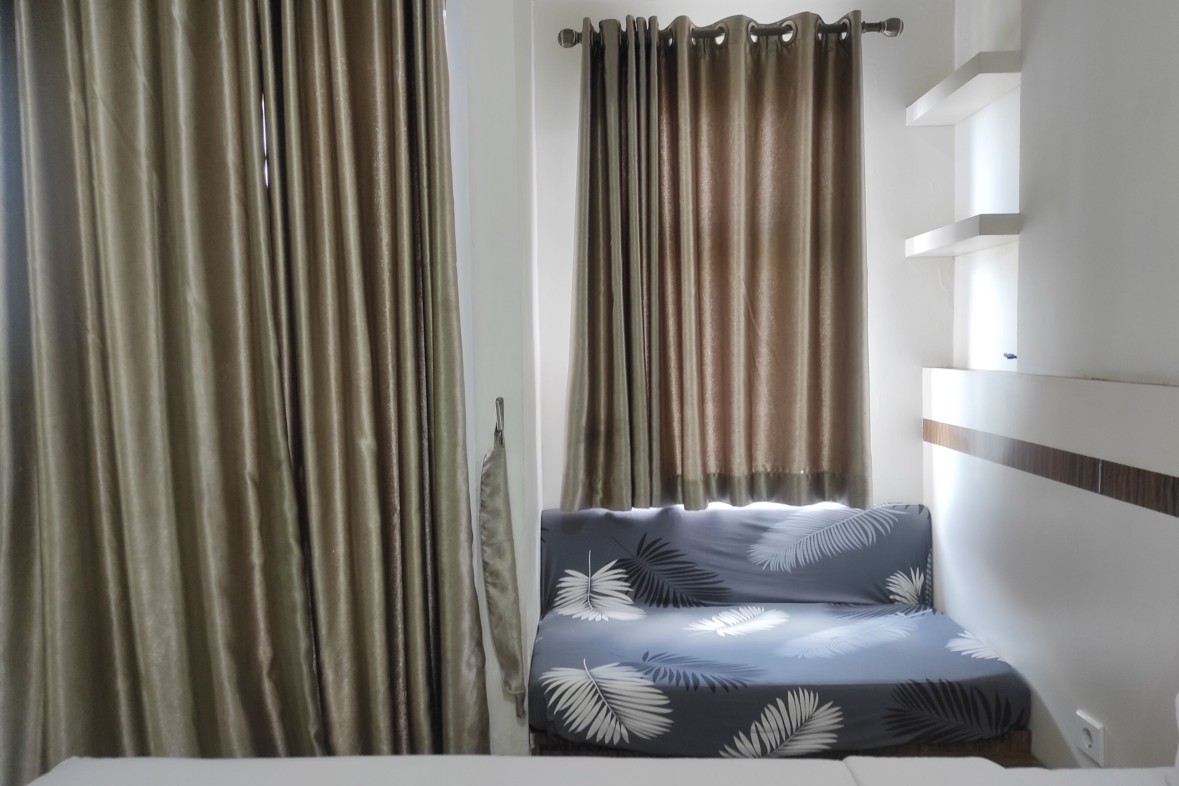 A room with a bed, curtains, and a shelf unit.