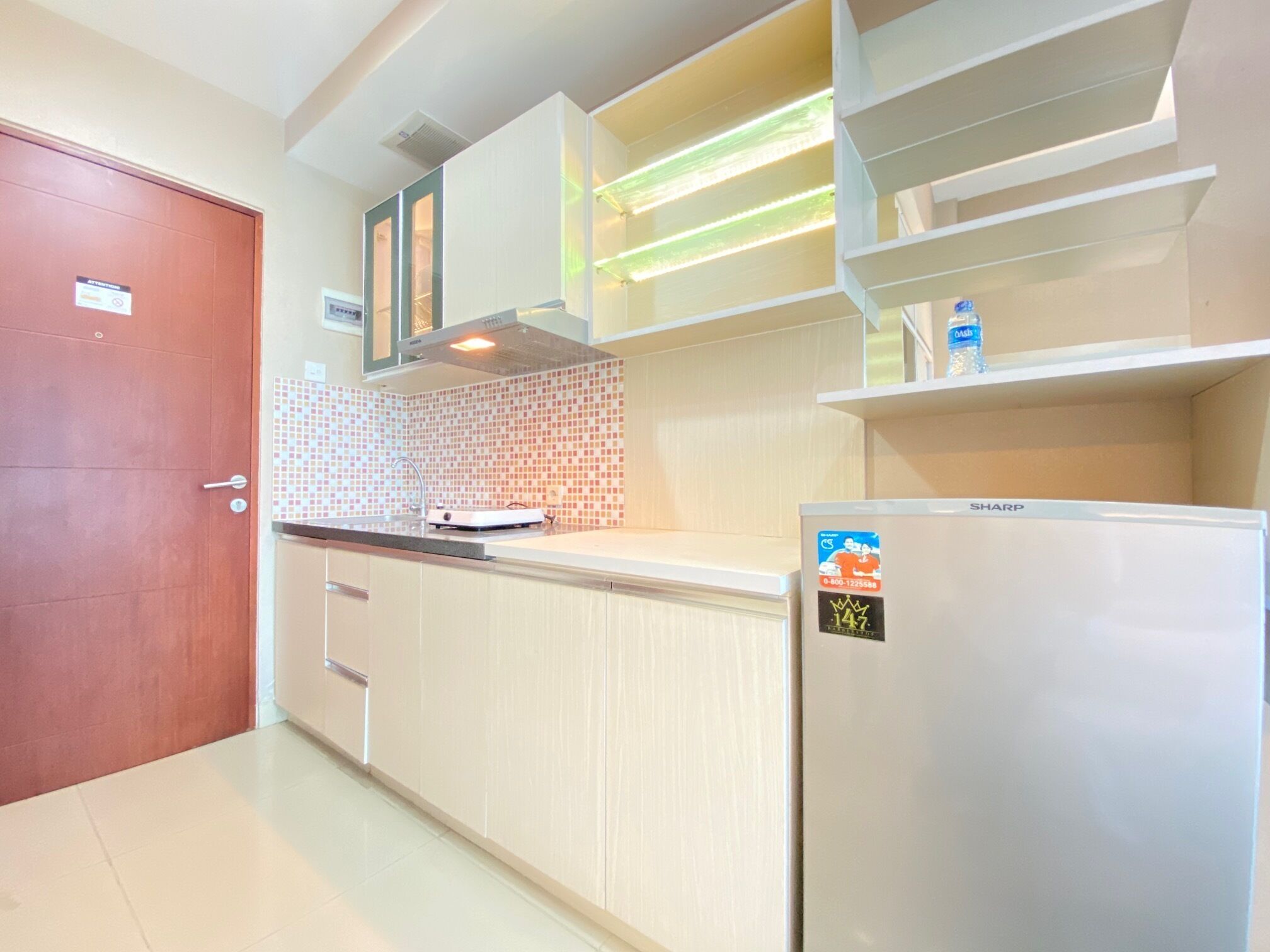 A modern kitchen with a built-in microwave, a refrigerator, and a tiled backsplash.