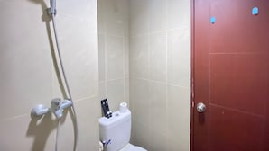 A bathroom with a shower, toilet, and a red door. - Cozy And Spacious Studio Apartment At Taman Melati Jatinangor (Hegarmanah)
