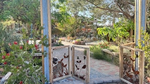 A wooden pergola structure with a decorative metal gate featuring animal silhouettes. - Ultimate relaxation on 4+ acres, hot tub, projector/game room, BBQ, stars, moon (Yucca Valley)