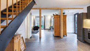 A modern kitchen with a built-in refrigerator, wooden cabinets, and a staircase with a metal railing.