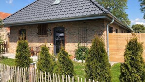 A brick house with a sloped roof, a small window, and a wooden fence.