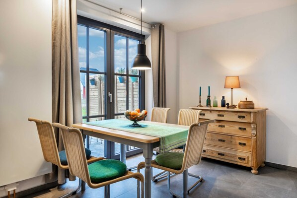 Un coin repas comprenant une table, des chaises, une lampe et une commode.