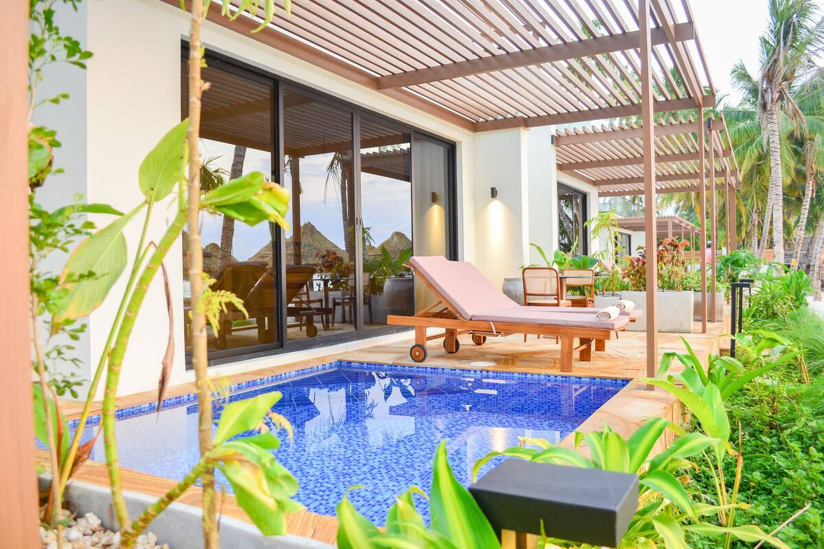 A poolside area with a lounge chair, a table, and a pergola.