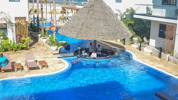 Relax by the pool surrounded by lounge chairs and lush greenery under a thatched umbrella.