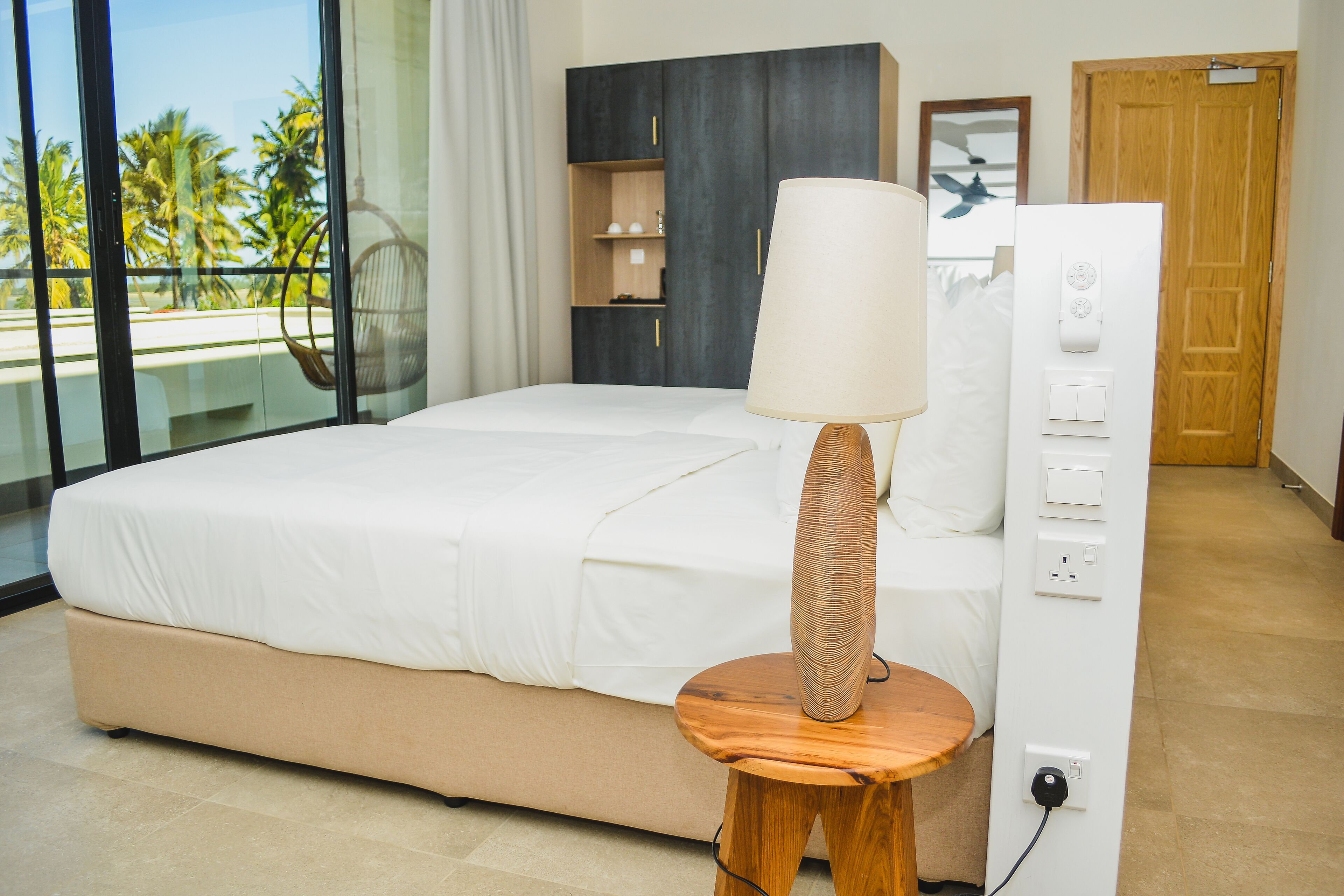 A bedroom with a bed, a bedside table with a lamp, a wardrobe, and a power outlet.
