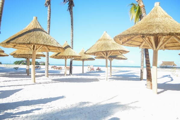 On the beach, white sand, sun-loungers, beach umbrellas