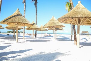 On the beach, white sand, sun loungers, beach umbrellas