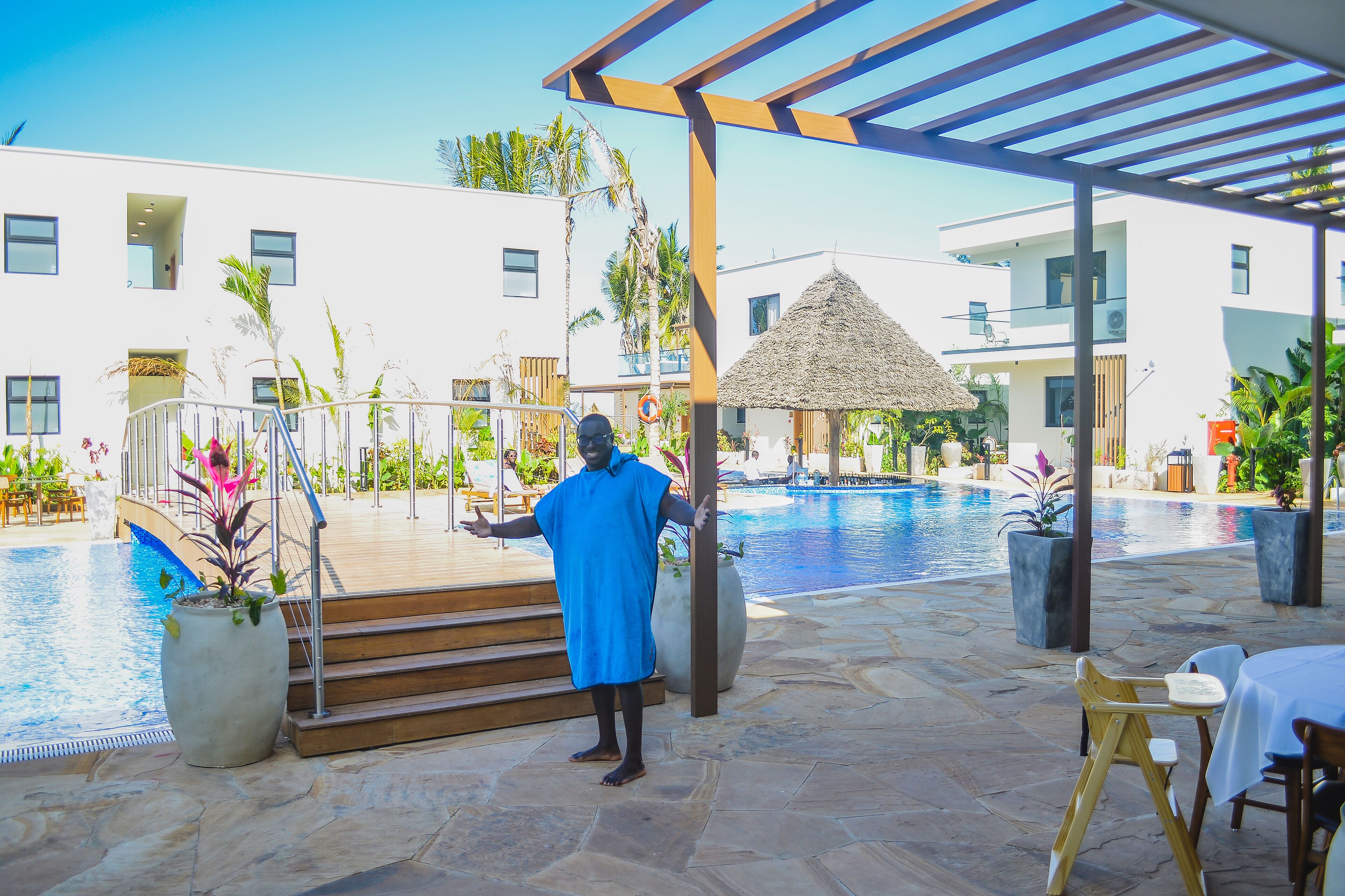 A poolside area with a covered seating area, a pool, and a building with multiple windows and balconies.