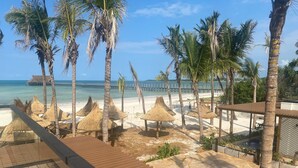 A beach resort with thatched umbrellas, a pool, palm trees, and a pier in the background. - TOA Hotel & Spa Zanzibar (Pongwe)