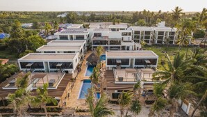A resort with multiple modern buildings, a central pool, and surrounding palm trees. - TOA Hotel & Spa Zanzibar (Pongwe)