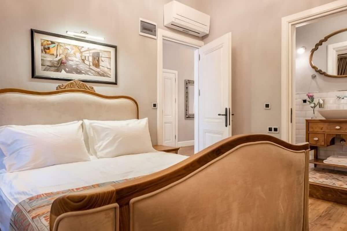 Una camera da letto con un letto, un comodino, uno specchio e una porta che dà su un'altra stanza.