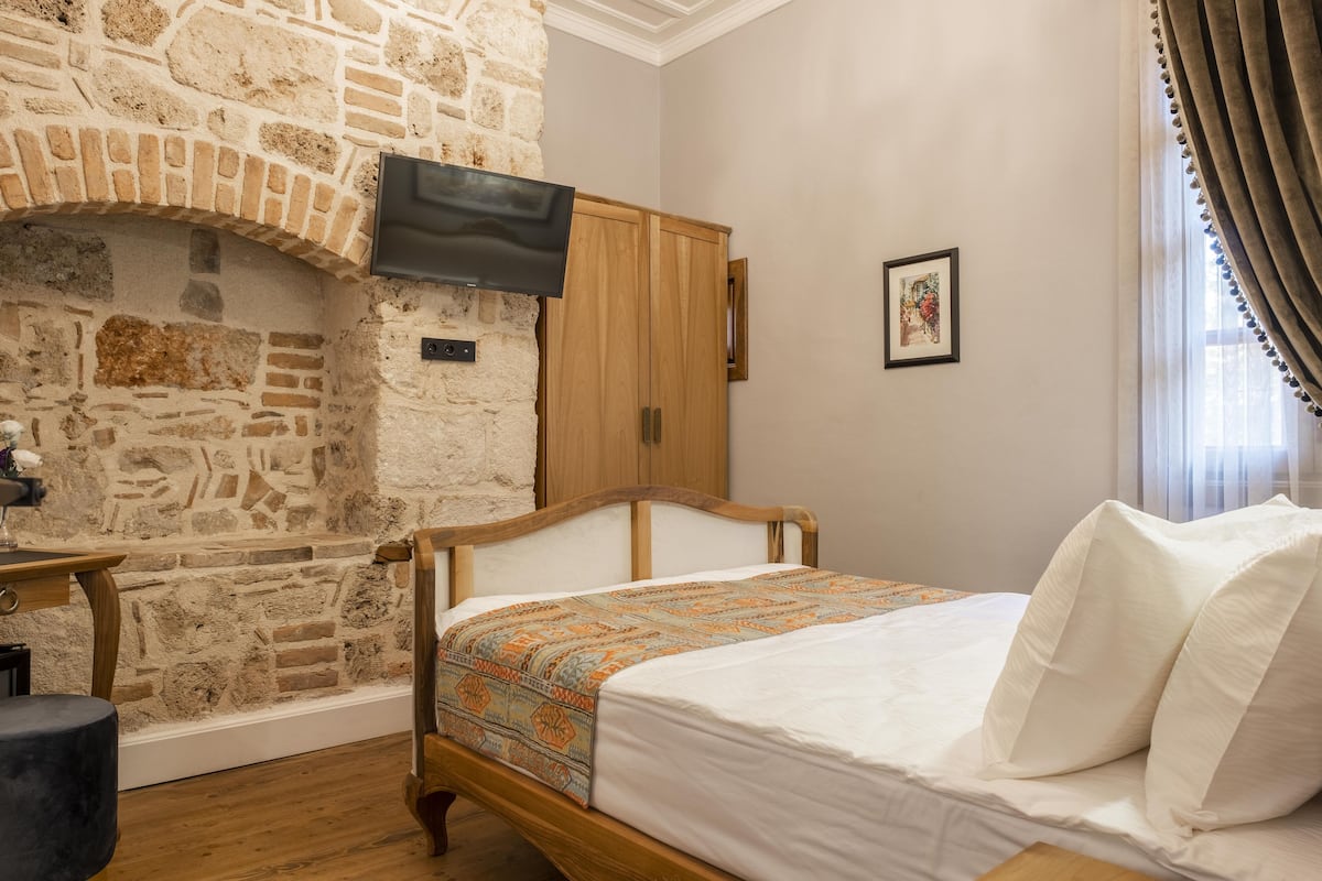 Una camera da letto con camino in pietra, letto di legno e TV a parete.