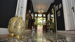 Um corredor com vasos ornamentados, um candelabro e vista para o exterior.