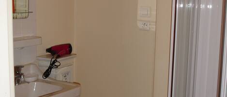 A bathroom with a sink, mirror, and a hairdryer on the counter.