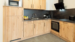 Una cocina moderna con armarios de madera, microondas, fregadero, estufa y cafetera.
