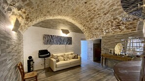 Uma sala de estar moderna com um arco de pedra, um sofá branco, uma poltrona preta e uma mesa de jantar de madeira.