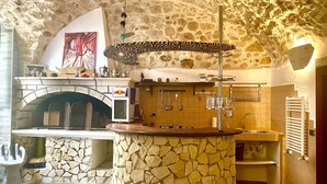 Uma cozinha com piso de pedra, forno embutido, uma ilha de pedra com um guarda-sol estampado com padrão zebra e painel de azulejos.