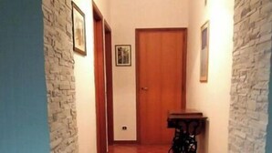 A hallway with stone walls, a wooden door, and a small table with a lamp. - Miscale House (Cattolica Eraclea)