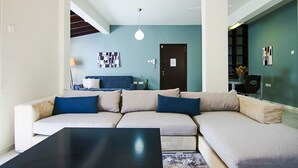 A modern living room with a sectional sofa, a black coffee table, and artwork on the walls. - City View Luxury Flat Harbour 04 (Larnaca)