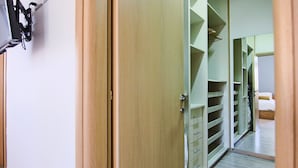 A room with a wooden door, a mirror, and a closet with shelves and drawers. - City View Luxury Flat Harbour 04 (Larnaca)