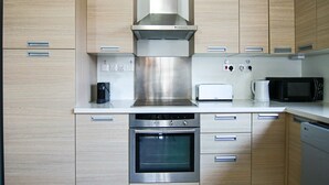 A modern kitchen with stainless steel appliances, wooden cabinets, and a built-in oven. - City View Luxury Flat Harbour 04 (Larnaca)