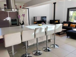 A modern kitchen with a central island, stainless steel appliances, and a black stove.