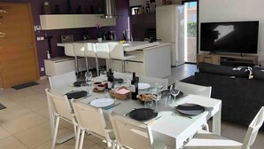 A modern living space with a dining area, kitchen, and a TV.