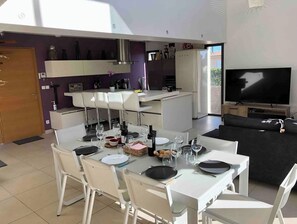 A modern living space with a dining area, kitchen, and a TV.