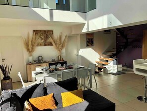 A modern living space with a dining area, a staircase, and a sofa with cushions.