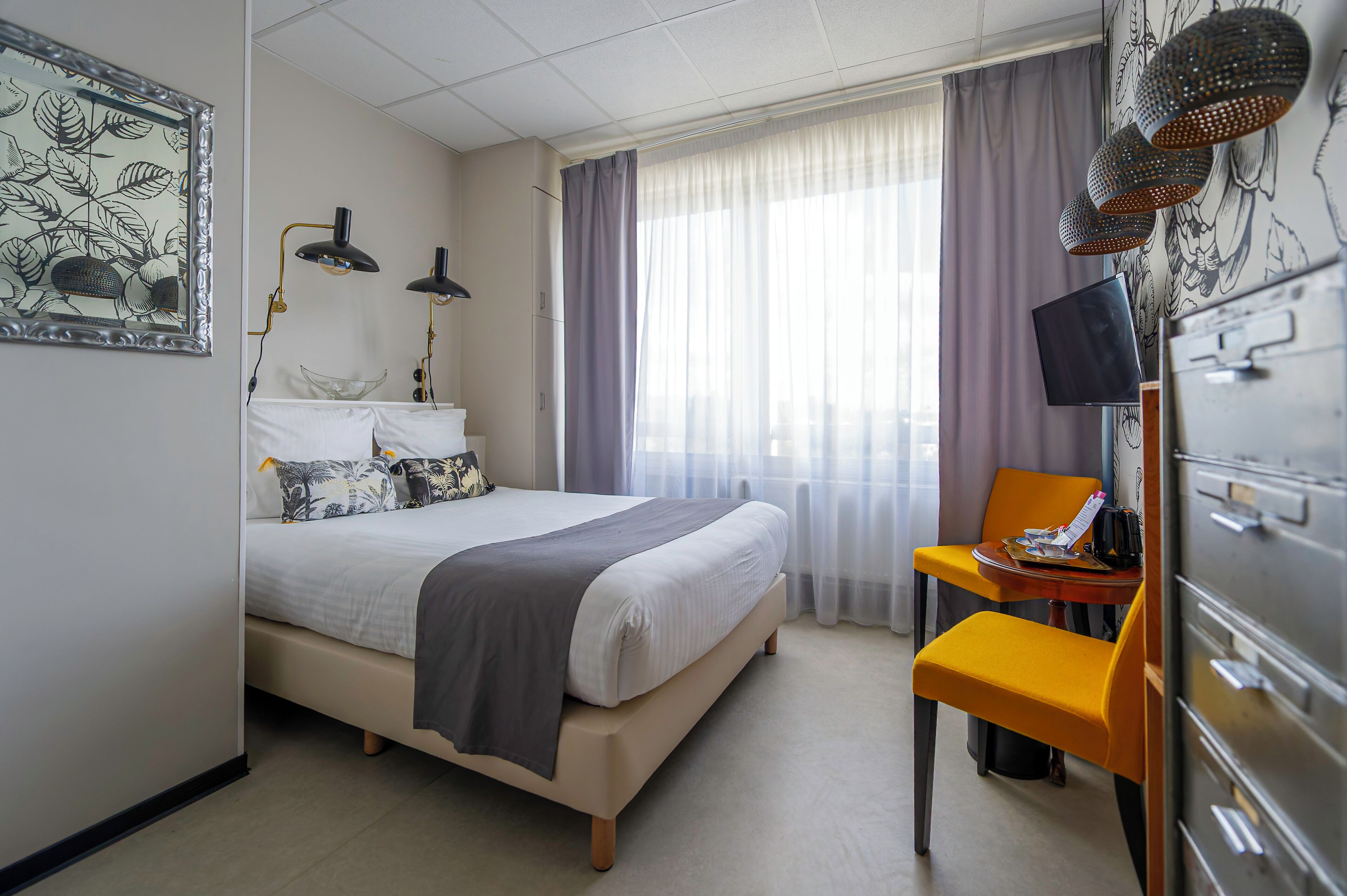 Une chambre d’hôtel comprenant un lit, un bureau avec une chaise, une télévision et une armoire.
