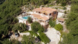 Una villa de estilo mediterráneo con piscina, varios balcones y un camino de piedra.