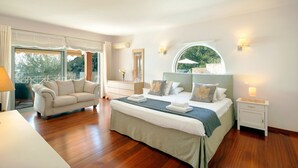 Un dormitorio amplio con una cama grande, un sofá y vistas a zonas verdes.