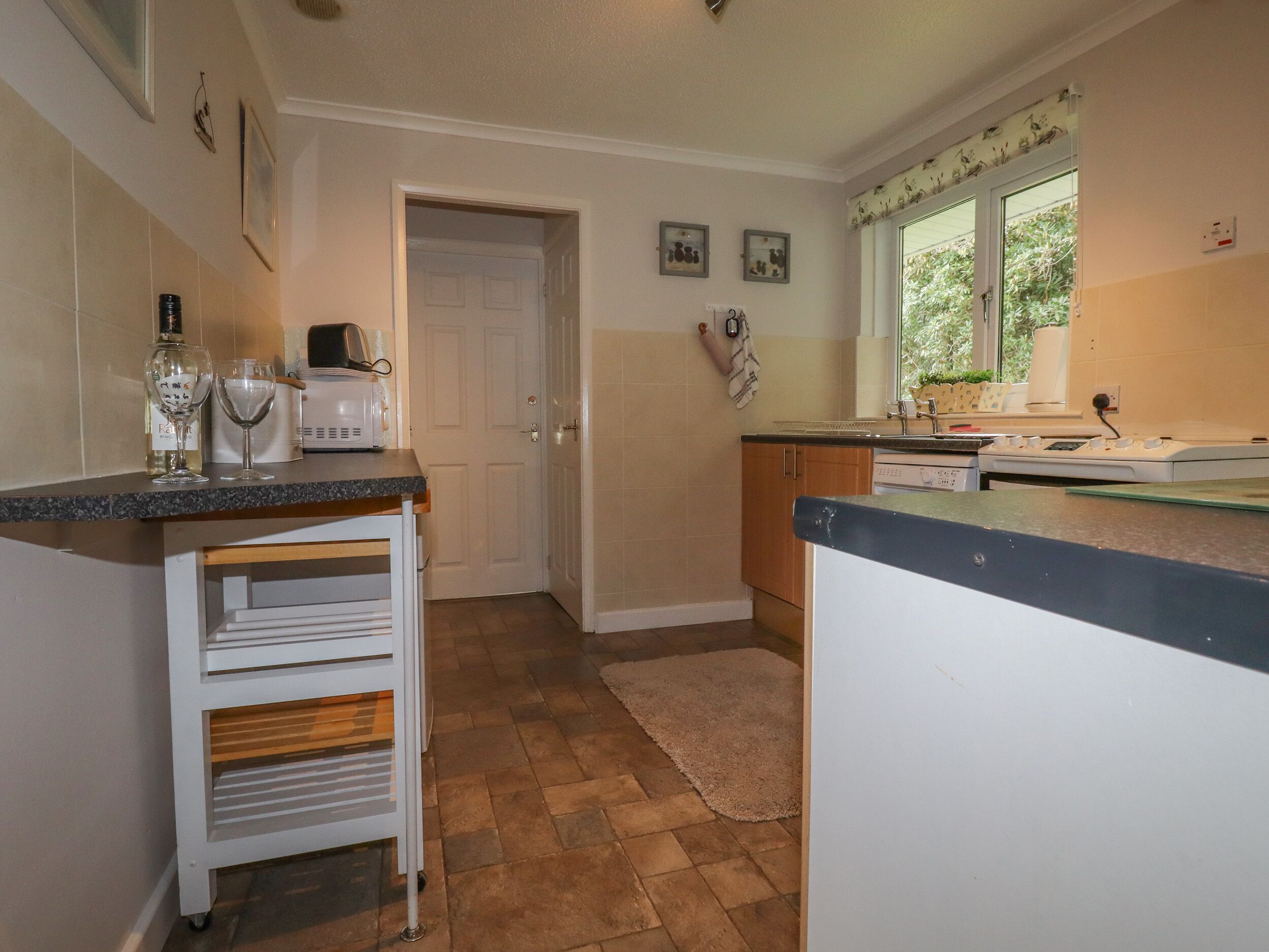 Una cocina con microondas, un armario blanco, una encimera y una puerta que da a otra habitación.