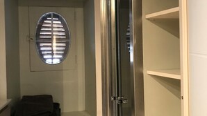 Una habitación con aire acondicionado incorporado, una puerta con espejo y una ventana con persianas.