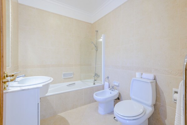 A modern bathroom with a bathtub, a sink, a bidet, and a toilet.
