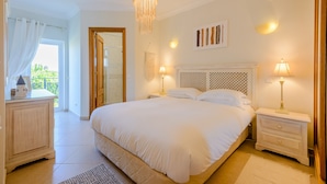 Un dormitorio con una cama grande, lámparas de noche, una mesita de noche, un aparador y vistas al exterior.