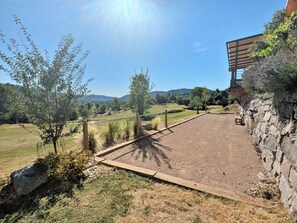 A gravel area with a wooden fence, a stone wall, and a bench. - Spacious cottage for 10 in Vagney - Sauna, games, near Gérardmer (Vagney)