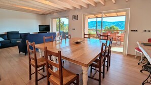 A spacious living room with a wooden dining table, chairs, a sofa, and a television. - Spacious cottage for 10 in Vagney - Sauna, games, near Gérardmer (Vagney)