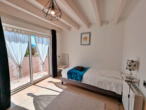 A bedroom with a bed, a bedside table, a radiator, a window with curtains, and a ceiling light fixture. - Spacious cottage for 10 in Vagney - Sauna, games, near Gérardmer (Vagney)