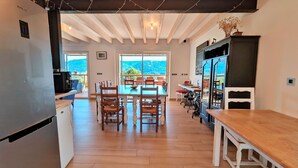 A modern kitchen with a built-in refrigerator, wooden dining table, and chairs. - Spacious cottage for 10 in Vagney - Sauna, games, near Gérardmer (Vagney)