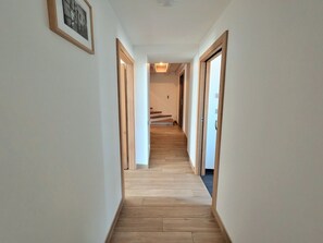 A hallway with wooden flooring, white walls, and framed pictures. - Spacious cottage for 10 in Vagney - Sauna, games, near Gérardmer (Vagney)