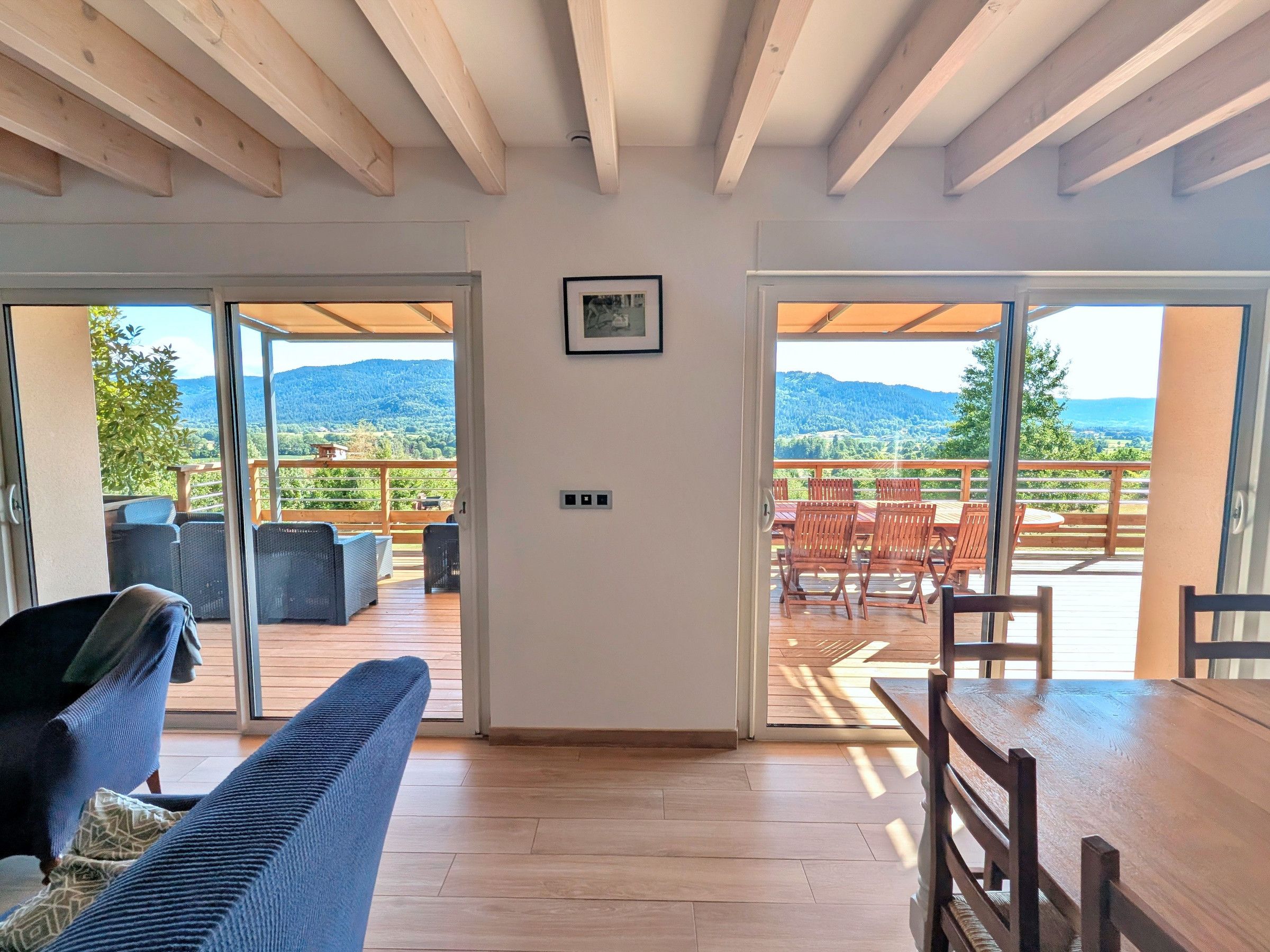 Ein geräumiges Zimmer mit einem großen Schiebeglasfenster, das auf eine Terrasse mit Bergblick führt.