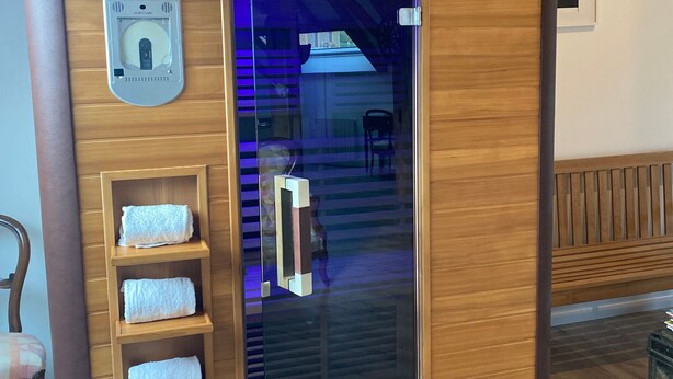 A sauna room with a control panel, wooden shelves with towels, and a glass door. - Spacious cottage for 10 in Vagney - Sauna, games, near Gérardmer (Vagney)